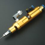 Valve de dosage industrielle en inox utilisée pour l’application précise de fluides liquides et pâteux sur une ligne de production automatisée.